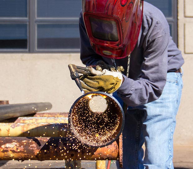 Student welding a large pipe.