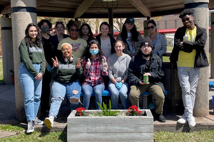 Phi Theta Kappa students taking a group photo in front of a planter box they installed on the campus.