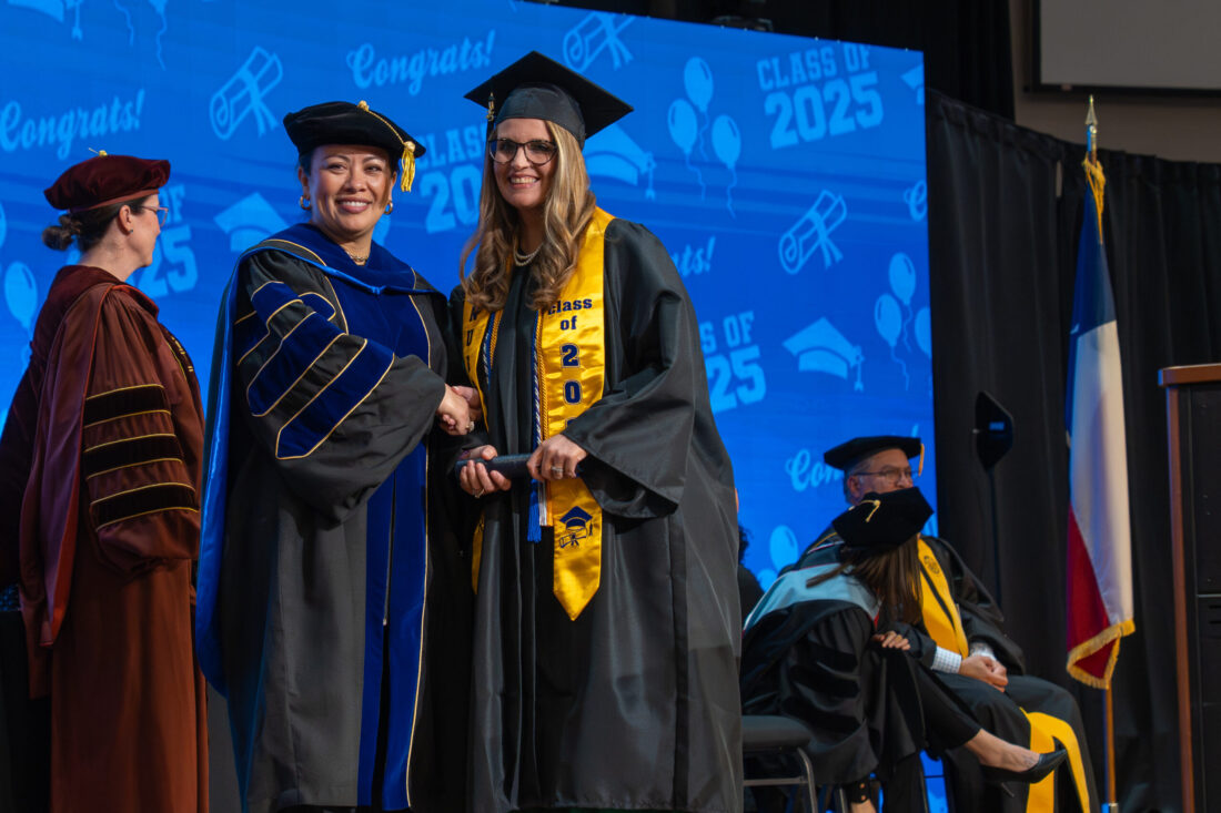 PHOTO: COM President Dr. Helen Brewer (left) poses with a graduate on stage at graduation.