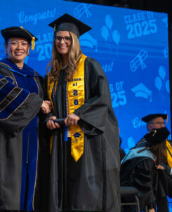 PHOTO: COM President Dr. Helen Brewer (left) poses with a graduate on stage at graduation.