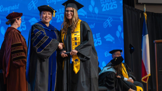 PHOTO: COM President Dr. Helen Brewer (left) poses with a graduate on stage at graduation.